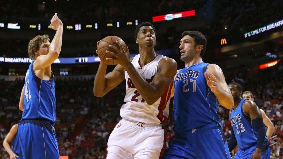 El centro del Heat Hassan Whiteside se abre paso entre Dirk Nowitzki, of the Dallas Mavericks (41) y Zaza Pachulia, de los Mavericks, en el AmericanAirlines Arena en Miami, el viernes 1 de enero del , 2016.