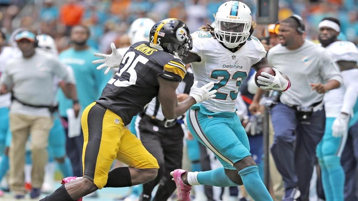 El running back de los Dolphins Jay Ajayi (23) corre para el primer down contra los Steelers de Pittsburgh Steelers y supera al cornerback Artie Burns (25), en el Hard Rock Stadium on Sunday, October 16, 2016.