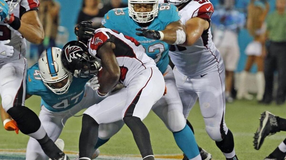 Ndamukong Suh (93), de los Dolphins, frena a Tevin Coleman (26), de los Falcons, en el primer cuarto del partido en el Camping World Stadium en Orlando, Florida, la noche del jueves 25 de agosto del 2016.
