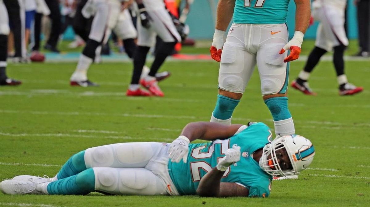 Kiko Alonso (47), de los Dolphins, mira a su compañero caído Raekown McMillan (52), quien se lesionó contra los Falcons, el jueves.