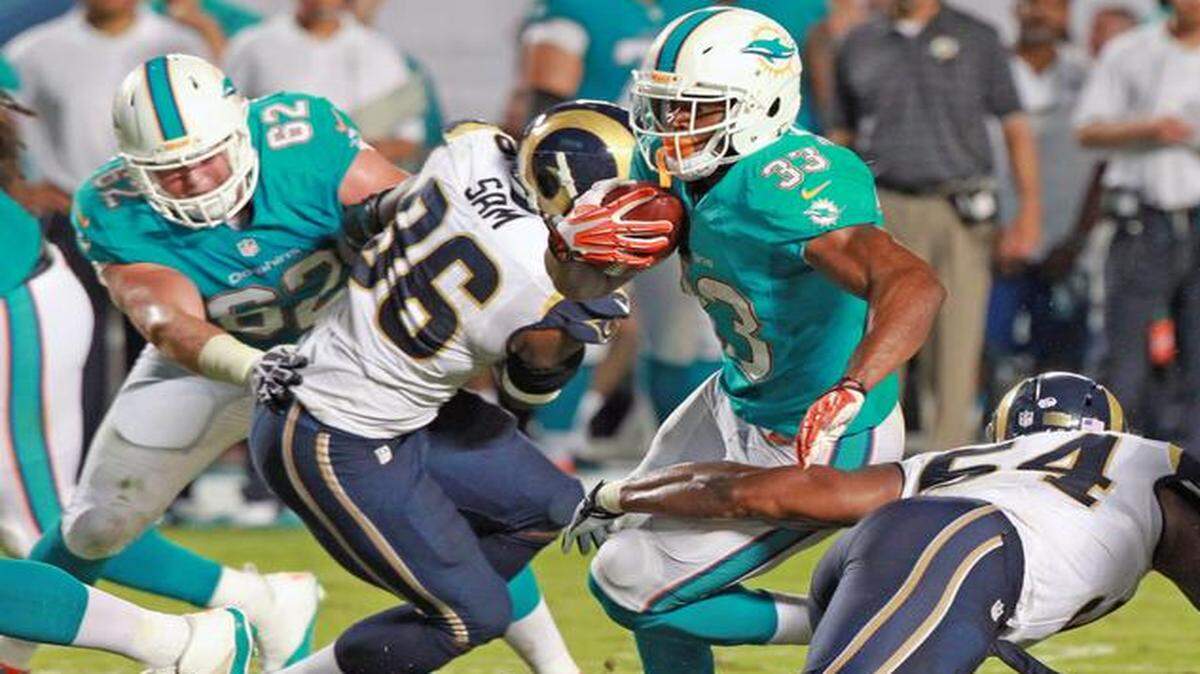 
Daniel Thomas (33) lucha contra Michael Sam (96) y Philip Steward (54), de los Rams de San Luis, en el Sun Life Stadium en Miami Gardens, el 28 de agosto del 2014.
