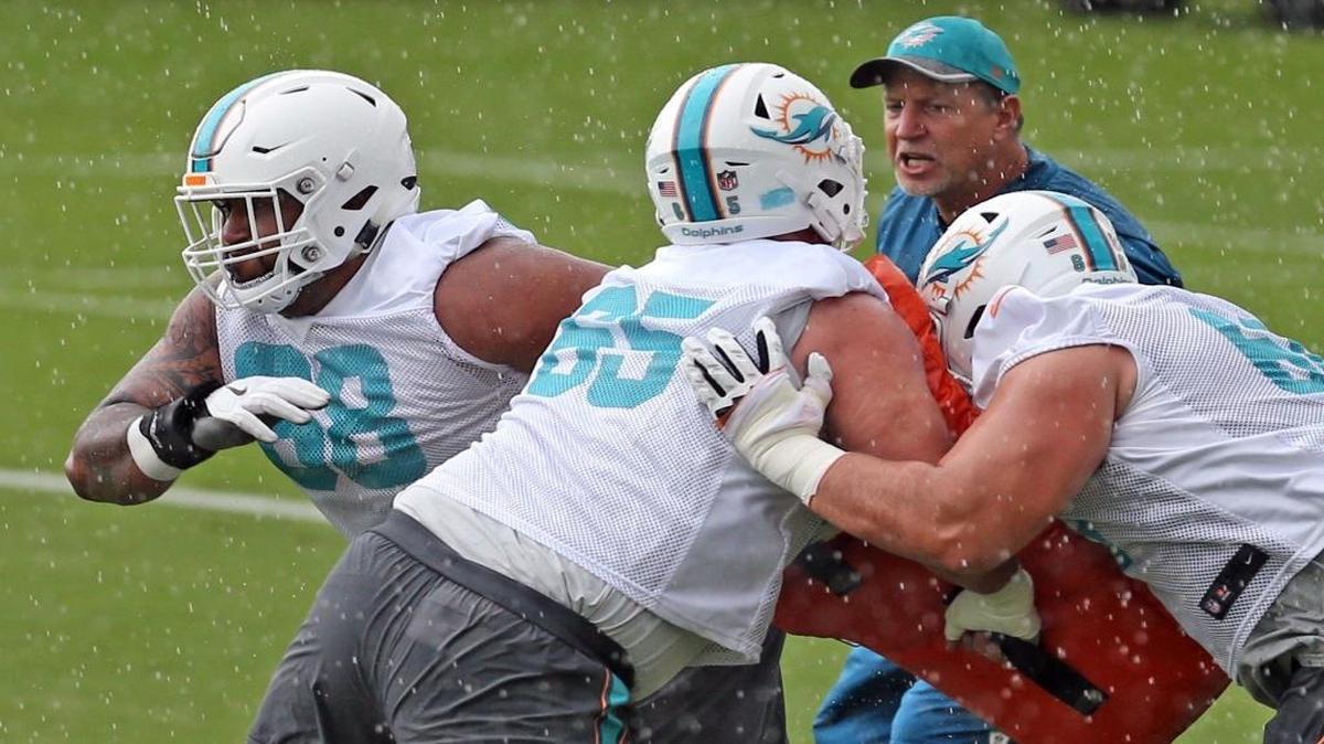 Bajo la lluvia, el guard Isaac Asiata (68) se entrena con otros compañeros ante la mirada de uno de los coachs, en el campamento de los Dolphins en Davie, Florida, el lunes 5 de junio del 2017.