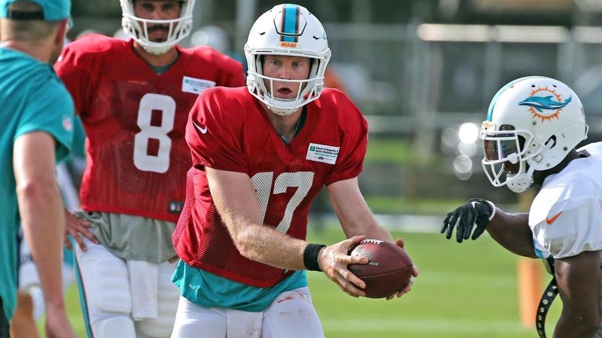 El quarterback de los Dolphins Ryan Tannehill (17) entrega un balón tras la mirada de su suplente Matt Moore (8) en la práctica del 3 de agosto en Davie.