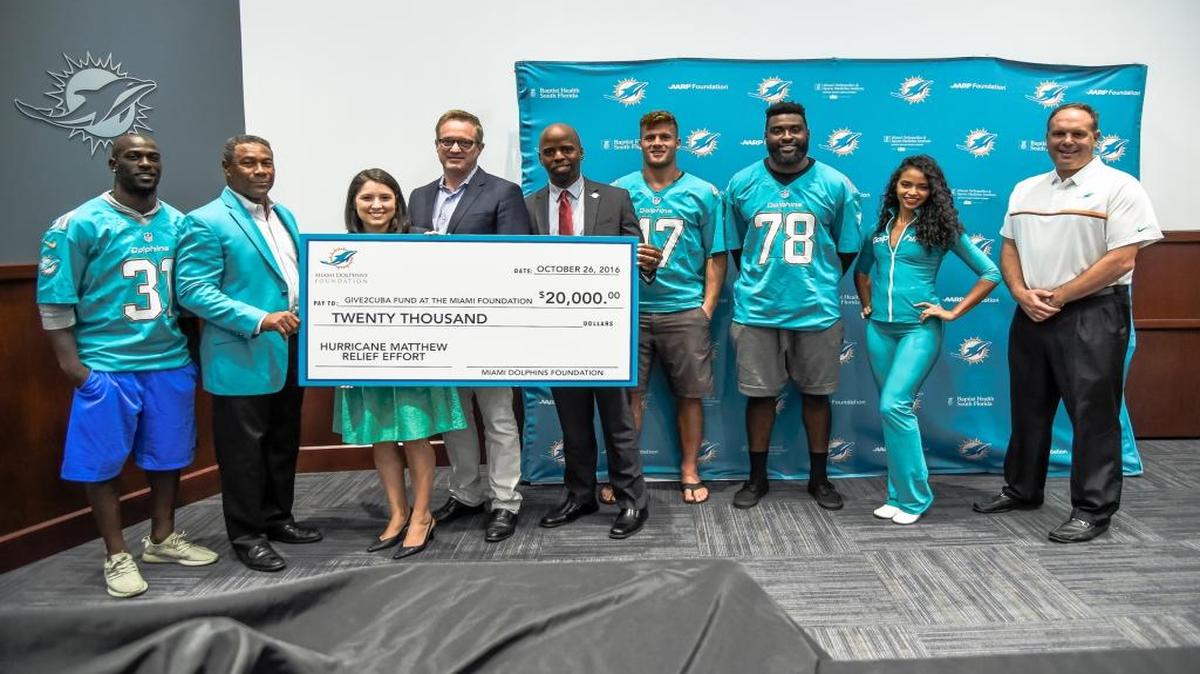 Un cheque de $20,000 para Cuba. Michael Thomas, Nat Moore, Janell Kaplan, Tom Garfinkel, Jason Jenkins, Kiko Alonso, Terrence Fede, Amina y Mike Tannenbaum (de izq.a der.).