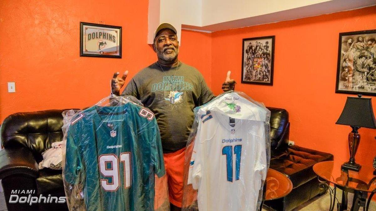 El veterano del ejército de Estados Unidos Joe Reddick muestra dos camisetas del equipo de Miami, que ayudó a reconstruir su casa, el jueves 3 de noviembre. La iniciativa fue de los Miami Dolphins, Bank of America, AARP Foundation y Miami-Dade Rebuilding Together.