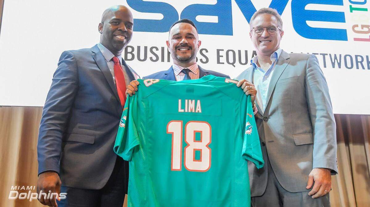 SAVE Executive Director Tony Lima holds a No. 18 jersey with his name, flanked by Jason Jenkins, executive vice president of communications and community affairs for the Dolphins, and Tom Garfinkel, chief executive of the Miami club.