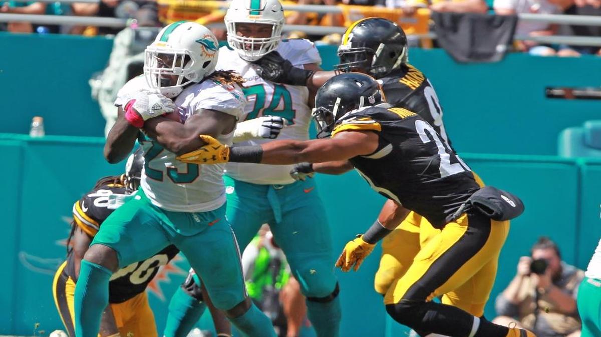 Jay Ajayi, de los Dolphins, asegura el ovoide, perseguido por Mike Mitchell (23), de los Steelers, mientras Jermon Bushrod (74) protege al corredor de Miami, en el segundo cuarto en el Hard Rock Stadium en Miami, el domingo 16 de octubre del 2016.