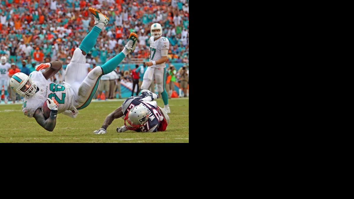 
El running back de los Dolphins Knowshon Moreno vuela sobre el jugador de los Patriots Tavon Wilson, el domingo en Miami. 
