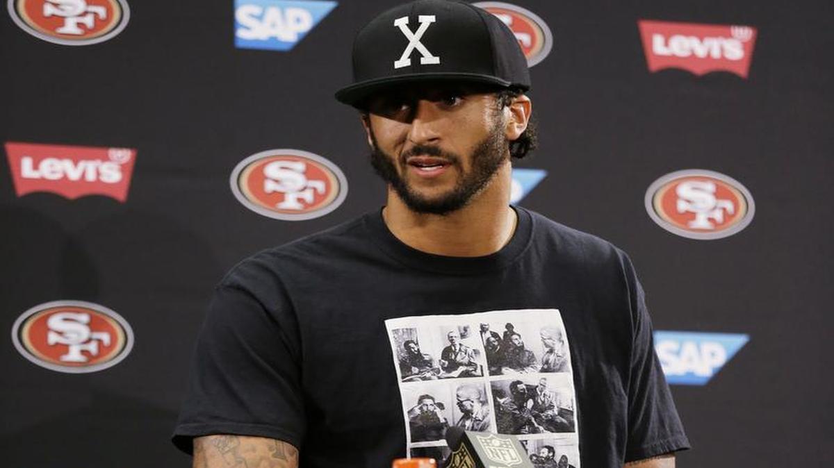 El quarterback de los 49ers de San Francisco Colin Kaepernick habla con los reporteros luego del partido de pretemporada contra los Packers de Green Bay, el 26 de agosto del 2016, en Santa Clara, California. Viste una camiseta con las imágenes de Malcolm X y Fidel Castro.