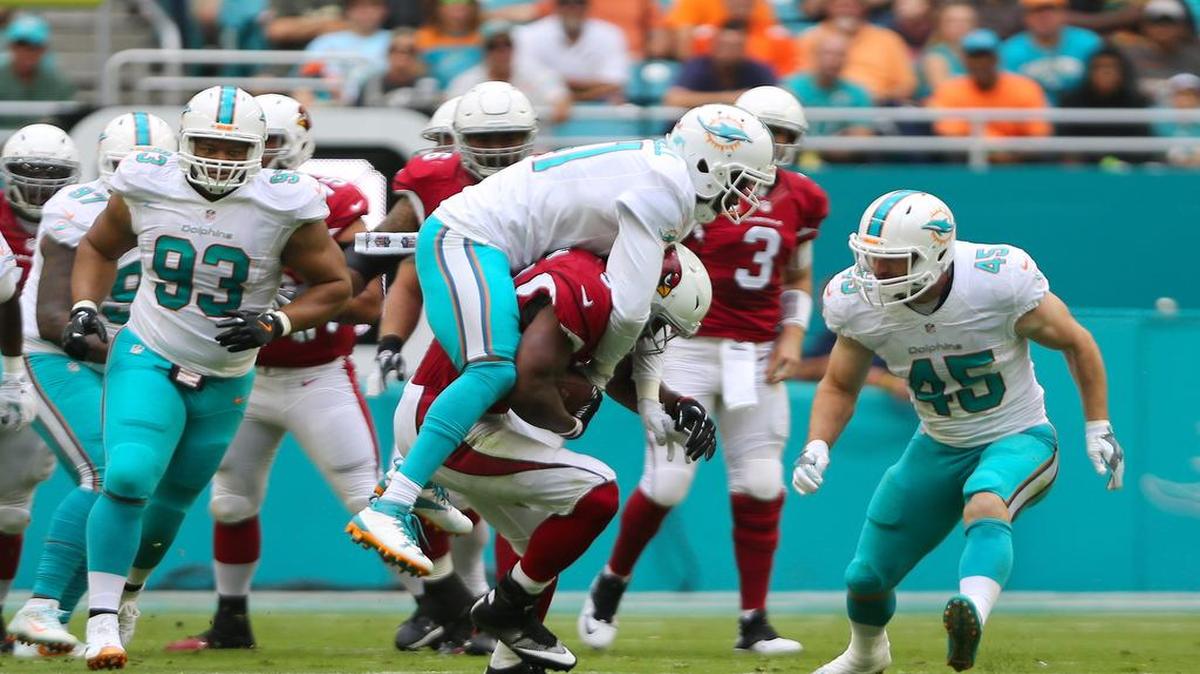 El cornerback de los Dolphins Byron Maxwell (centro) derriba al running back de los Cardinals de Arizona, en el partido efectuado en el Hard Rock Stadium de Miami Garden, el 11 de diciembre del 2016.