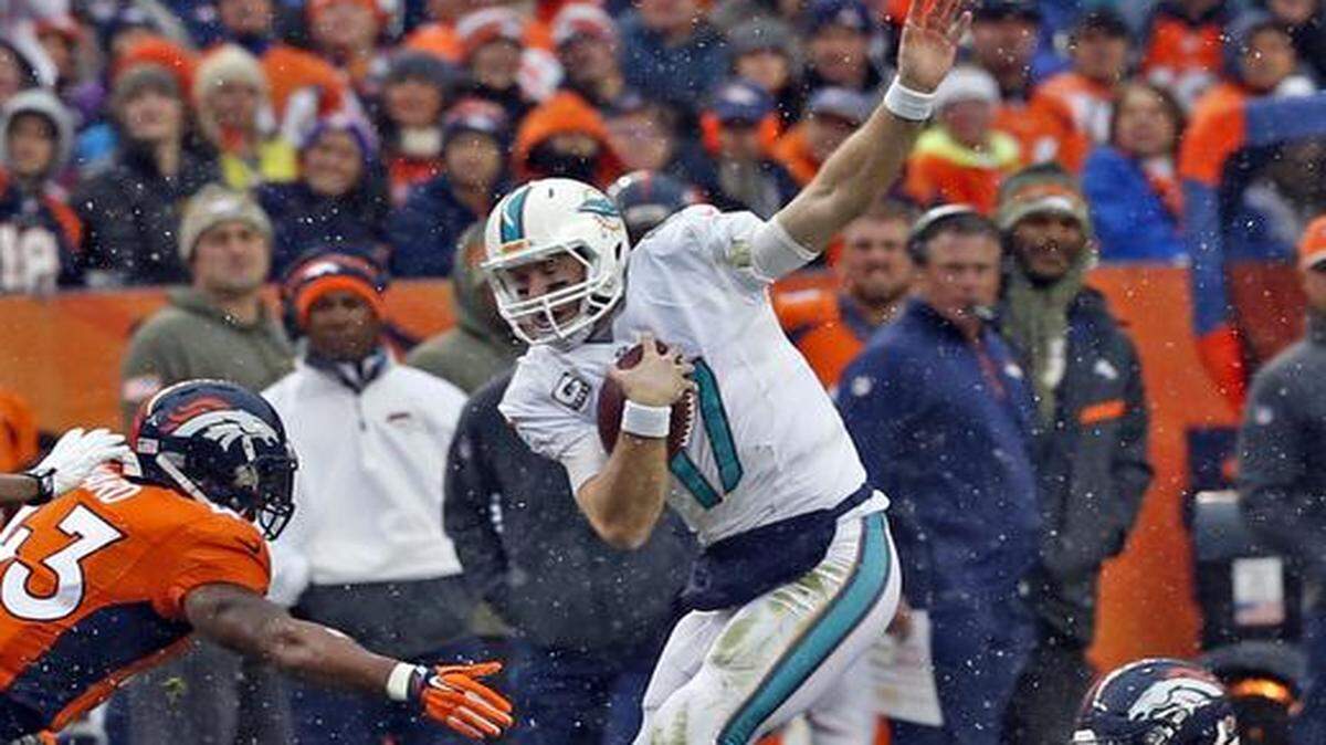
El quarterback de los Dolphins Ryan Tannehill (centro) trata de evadir al jugador de los Broncos T. J. Ward, en el segundo cuarto del partido efectuado el pasado domingo en el Sports Authority Field de Denver, Colorado.


