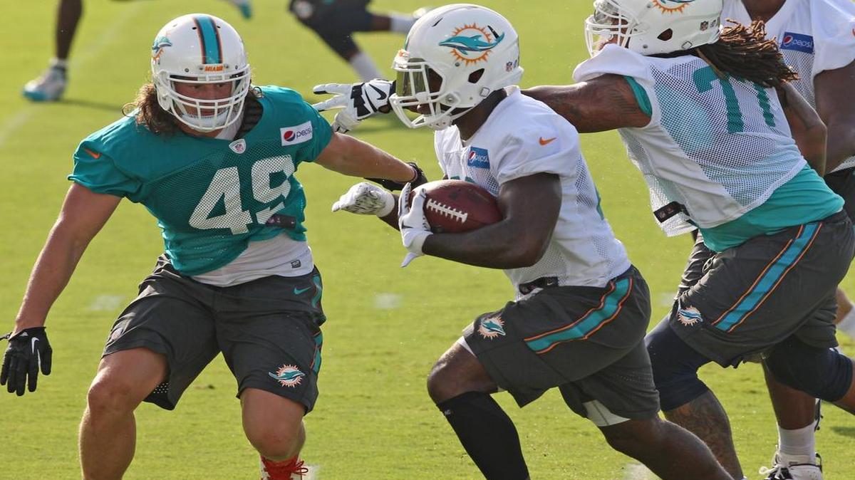 
Lamar Miller corre frente a Zach Vigil, en la práctica de los Dolphins, el jueves.
