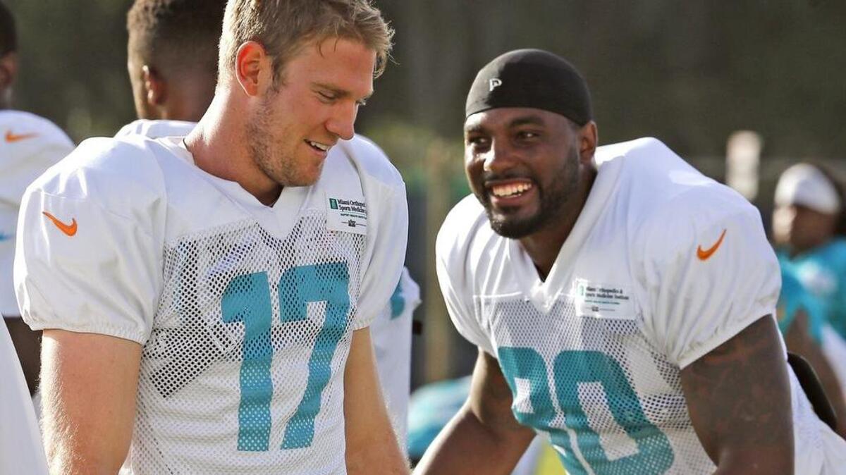 Ryan Tannehill (17) y Dion Sims sonríen durante los calentamientos en las prácticas de los Dolphins, el lunes.
