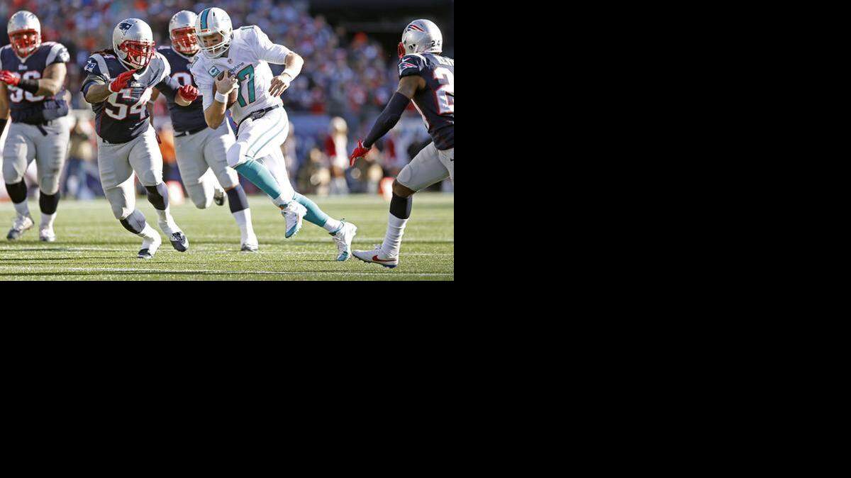 
El quarterback de los Dolphins Ryan Tannehill (#17) corre con el ovoide ante la presión de los jugadores de los Patriots, el domingo en el Gillette Stadium, en Foxborough, Massachusetts.


