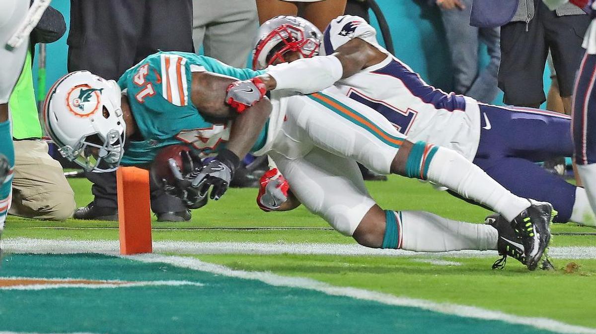 Jarvis Landry (izq.) anota un touchdown para los Dolphins ante la marca de Jonathan Jones, de los Patriots, en el partido efectuado el 11 de diciembre de 2017 en el Hard Rock Stadium de Miami Gardens, Florida.