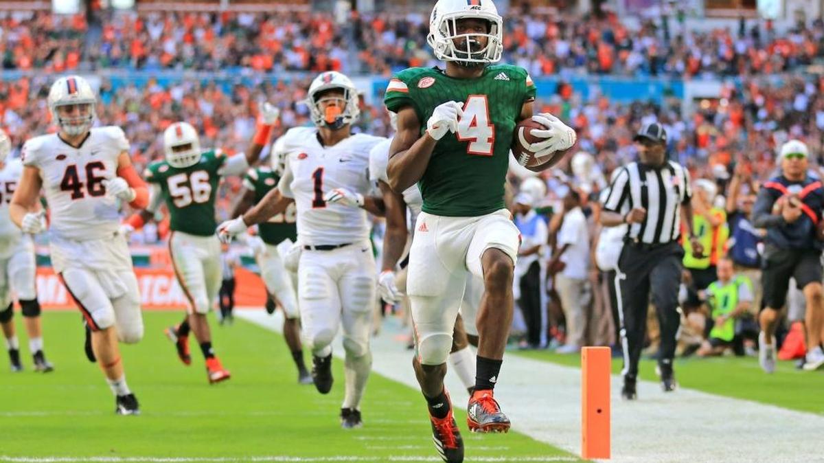 El defensive back de los Huracanes Jaquan Johnson (4) retorna una intercepción para anotar un touchdown clave en el tercer cuartoante los Cavalierde Viergina este sábado en el Hard Rock Stadium.