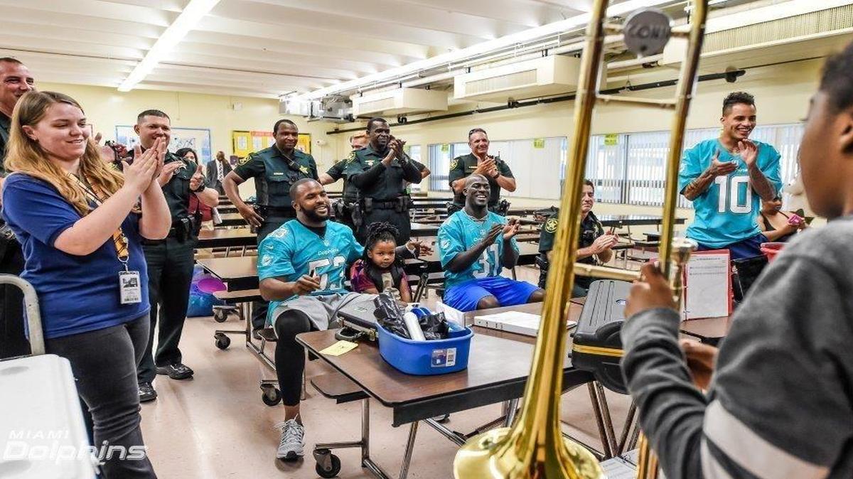 Los jugadores de los Dolphins Jelani Jenkins, Michael Thomas y Kenny Still (de izq. a der.) y miembros de la Oficina del Sheriff del Condado de Broward estuvieron en un colegio del sector para apoyar a los niños, el lunes 12 de diciembre del 2012.
