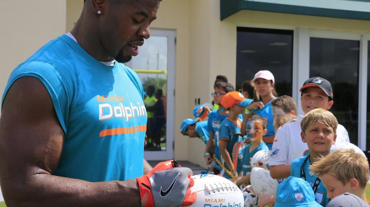 El defensive end Cameron Wake (91) firma autógrafos a un grupo de niños en el inicio del campamento de entrenamiento de los Dolphins, el viernes 29 de julio del 2016, en Davie, Florida.