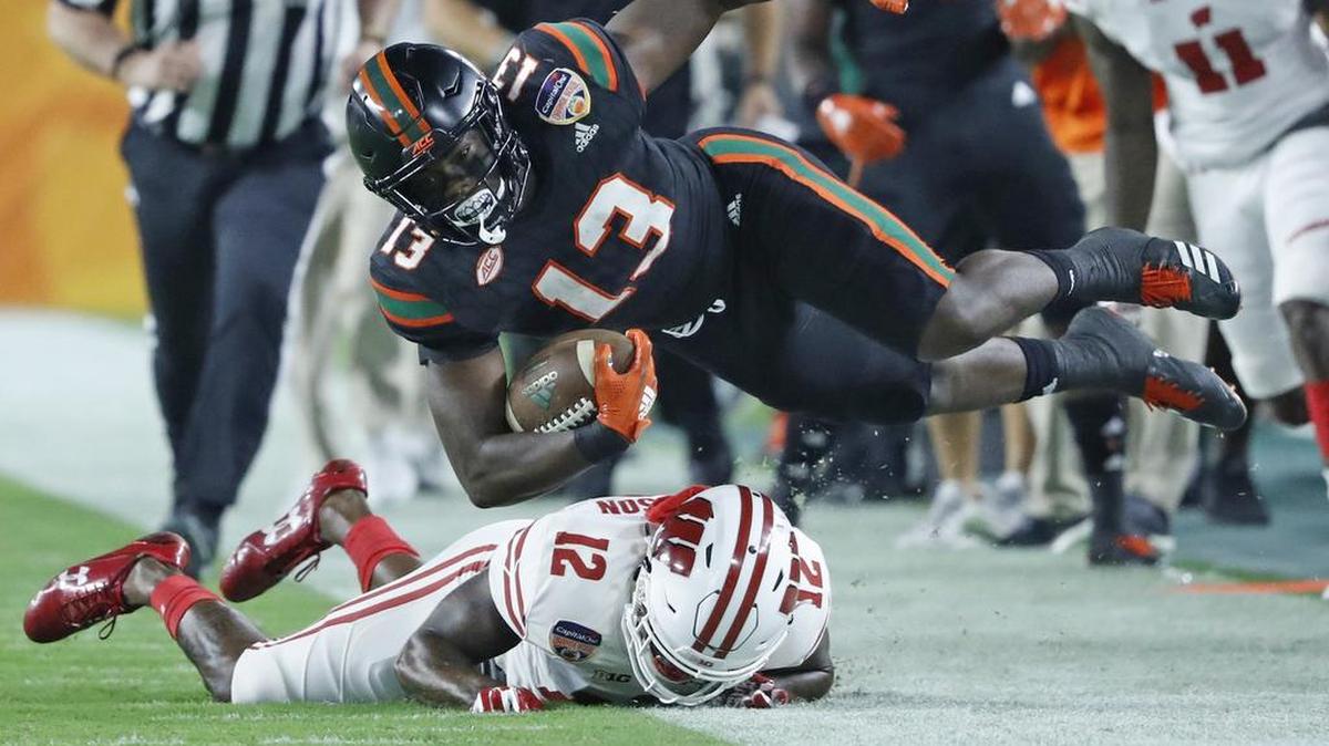 El running back DeeJay Dallas, de los Huracanes (13), consigue el primer down ante el safety Natrell Jamerson de los Badgers de Wisconsin este sábado en the Capital One Orange Bowl en el Hard Rock Stadium.