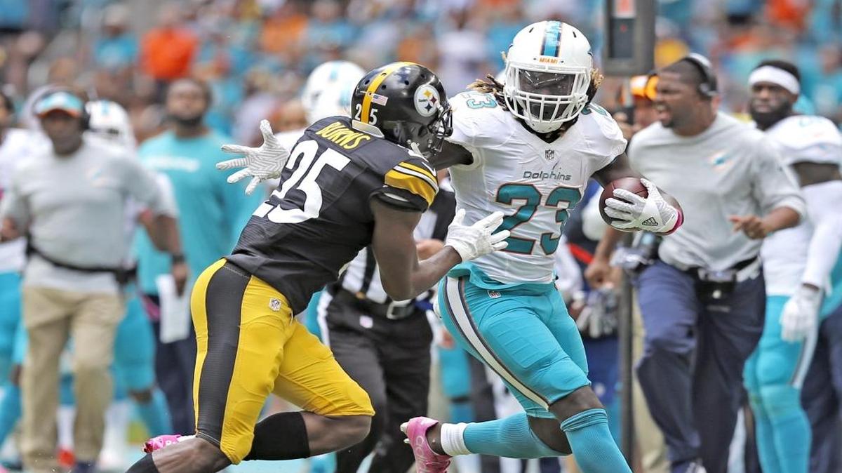 Jay Ajayi (23), de los Dolphins, corre contra Artie Burns (25), de los Steelers de Steelers, en el Hard Rock Stadium de Miami, el domingo 16 de octubre del 2016.