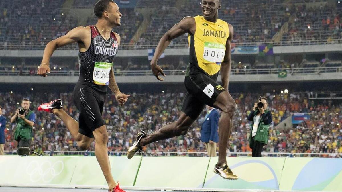 Usain Bolt,de Jamaica (der.) le sonríe al corredor de Canadá Andre De Grasse llegando a la meta en la semifinal de los 200m el miercoles en Río.