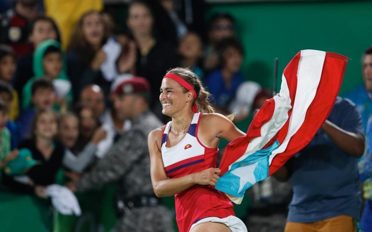 La tenista Mónica Puig levanta la bandera de Puerto Rico tras darle el primer oro olímpico el 13 de agosto del 2016, en Río de Janeiro, Brasil.