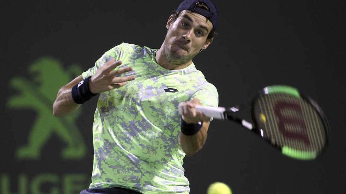 Guido Pella, de Argentina, returna la bola al búlgaro Grigor Dimitrov.