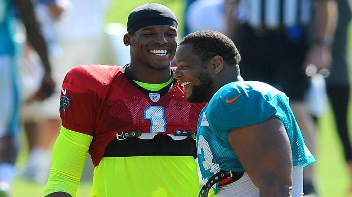 
El QB de los Panthers Cam Newton (izq.) bromea con el defensive tackle de los Dolphins Ndamukong Suh, el jueves.
