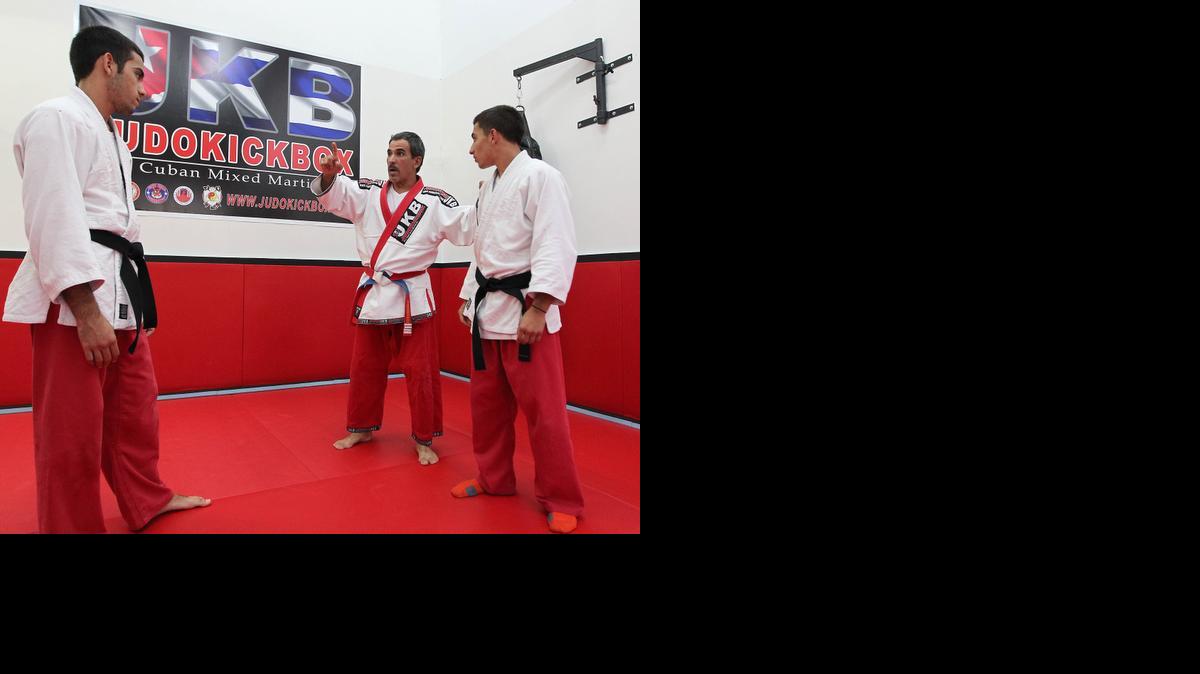 
Fraibel Hernandez, al centro, instructor de JudoKickBoxing explica a sus hijos Jayniel, izquierda, y Josniel Hernández, las técnicas de este arte marcial en JKB Grand Master Training Center de Miami.
