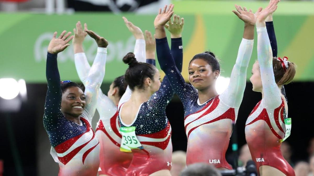 las integrantes del equipo femenino de gimnasia artística de EEUU Simone Biles (izq.), Gabrielle Douglas (C), Madison Kocian (R) saludan tras ganar la medalla de oro el martes en Río.