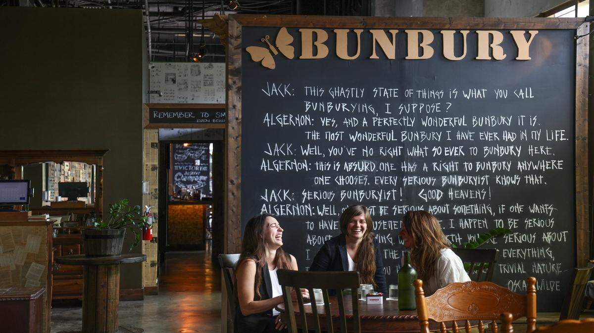 Las socias comerciales y pareja Paula Costa, centro, y Geraldine Quintero, izquierda, propietarias de Bunbury, y la gerente Alina Patalino, comparten un café y una conversación ligera influenciadas por su amor por la literatura, el vino y la familia, en el downtown de Miami a principios de marzo de 2023.