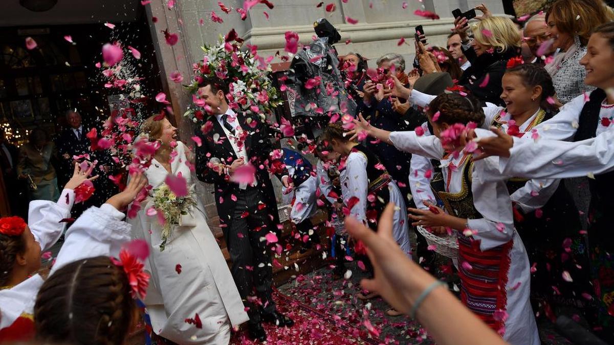 Invitados lanzan pétalos de rosa al príncipe Filip de Serbia, también conocido como Filip Karadjordjevic y su esposa Danica Marinkovic cuando salen de la catedral de Belgrado después de su ceremonia de boda el 7 de octubre de 2017.