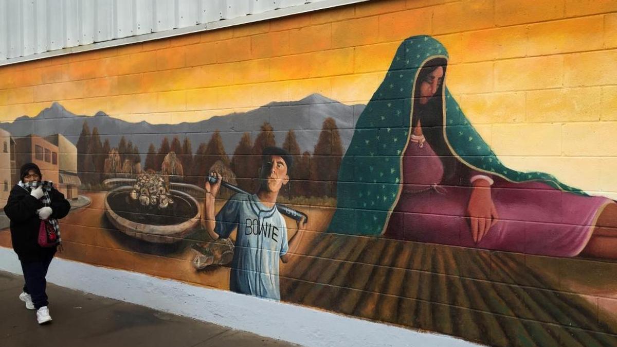 Un residente de Segundo Barrio de El Paso, Texas, pasa frente a un mural que refleja un tema chicano.