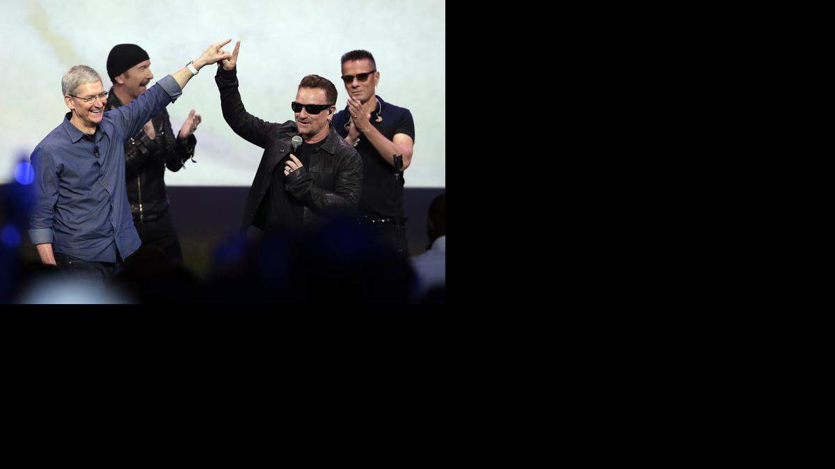 
Tim Cook, CEO de Apple (izq.), y Bono con U2, la durante la presentación de los iPhone6. 
