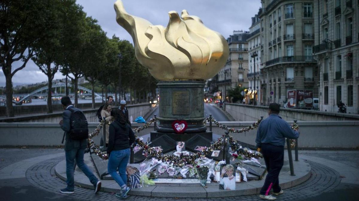 Personas observan los tributos a la princesa Diana puestos alrededor de la llama de la libertad sobre el túnel de Alma el miércoles 30 de agosto de 2017, en París (Francia).