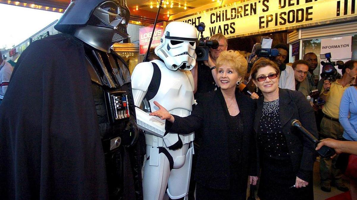 Fotografía de archivo del 12 de mayo de 2005 que muestra a la actriz estadounidense Carrie Fisher (d) junto a su madre, Debbie Reynolds (c) y dos personas disfrazados de personajes de "Star Wars2 durante el preestreno de "Star Wars III: La venganza de los Sith" en Washington, Estados Unidos. La actriz estadounidense Carrie Fisher, conocida por su papel de la princesa Leia en "Star Wars", falleció hoy a los 60 años.