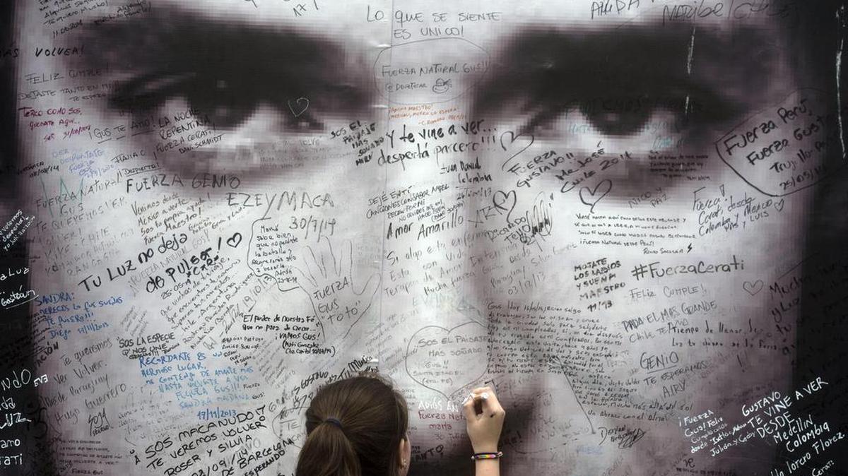 Una fanática del músico argentino Gustavo Cerati escribe un mensaje en un cartel con su imagen el 4 de septiembre de 2014, afuera de la Clínica ALCLA de Buenos Aires.