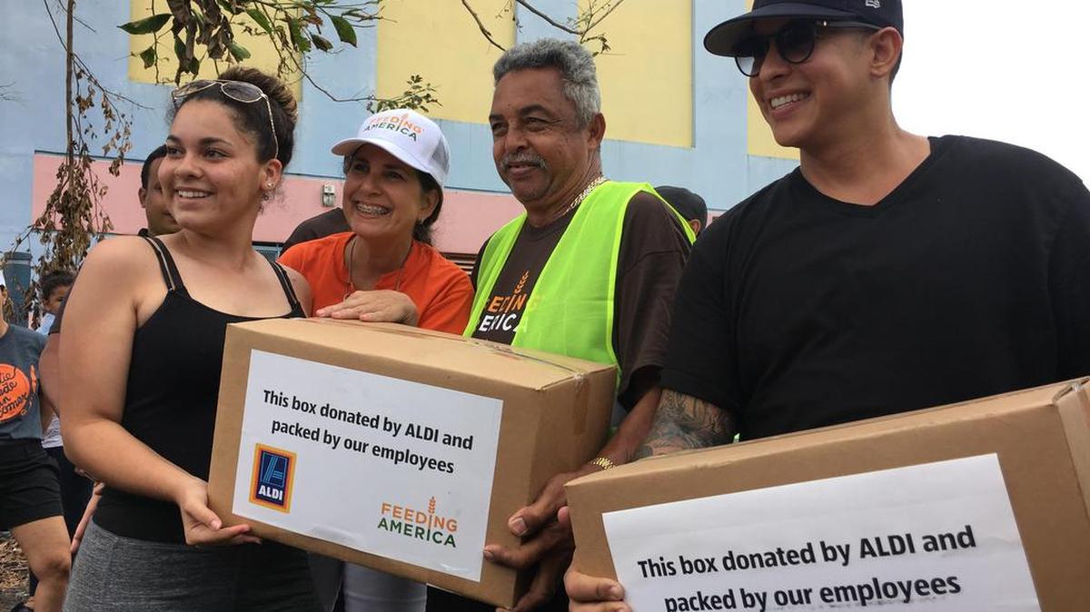 El cantante urbano Daddy Yankee (d) e integrantes del Banco de Alimentos de Puerto Rico entregan cajas de comida a ciudadanos afectados por el huracán María el sábado 30 de septiembre de 2017, en el municipio de Toa Baja (Puerto Rico).