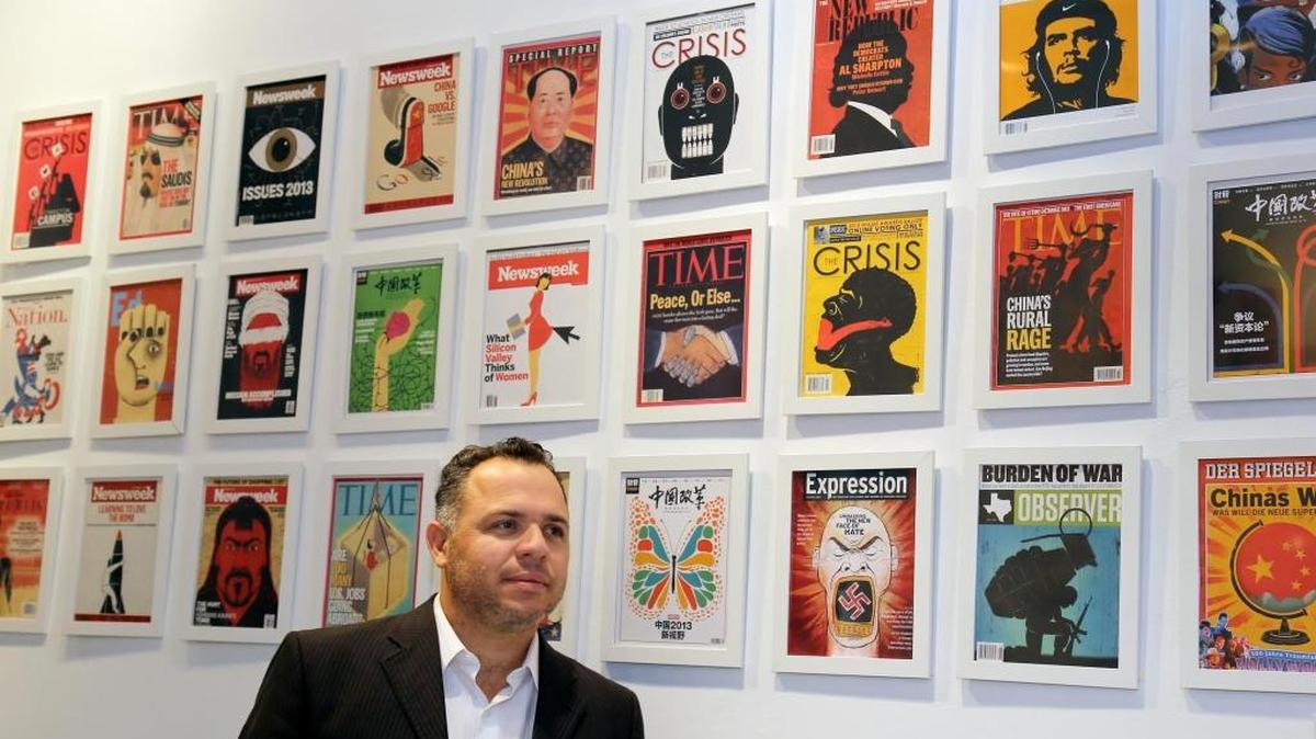 El ilustrador Edel Rodríguez posa ante sus portadas durante una exhibición en el Bronx Community College.