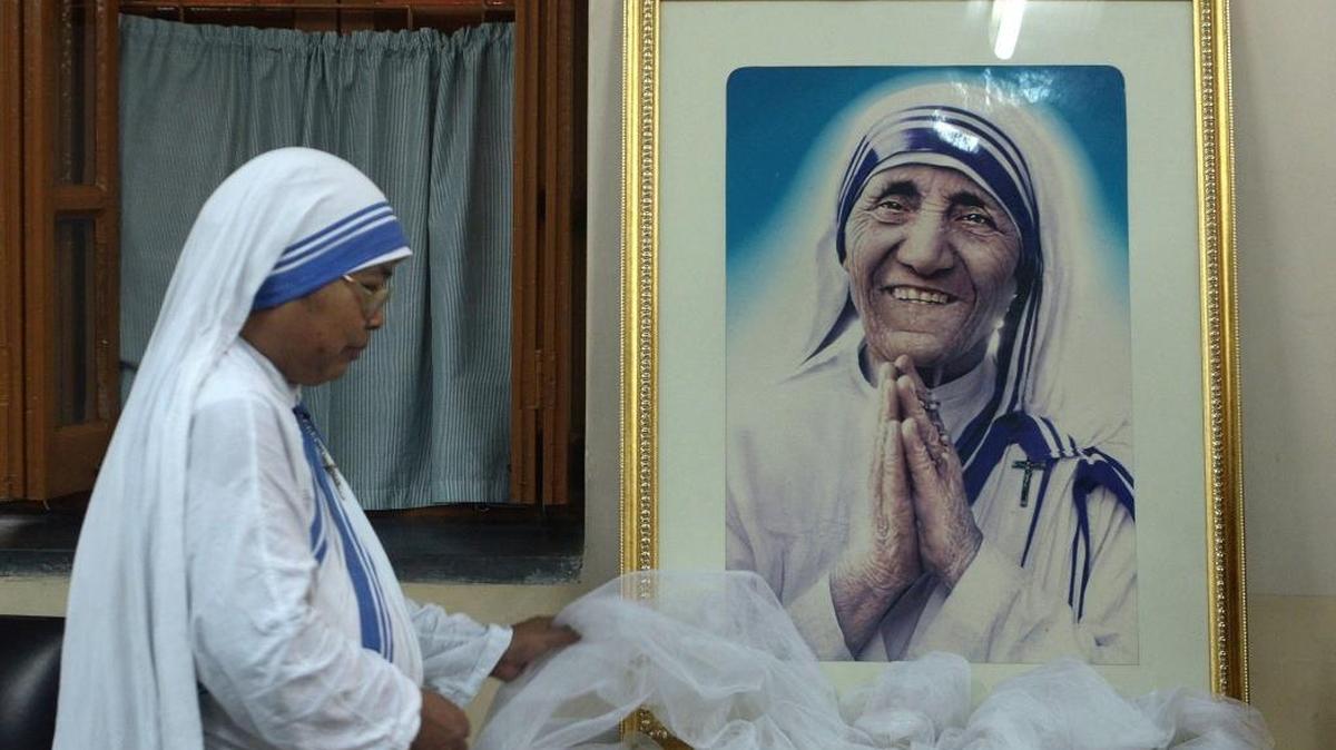 Una monja de las Misioneras de la Caridad decora un retrato de la Madre Teresa de Calcuta, hoy Santa Teresa, antes de una misa en Mother House en Kolkata en diciembre del 2015.