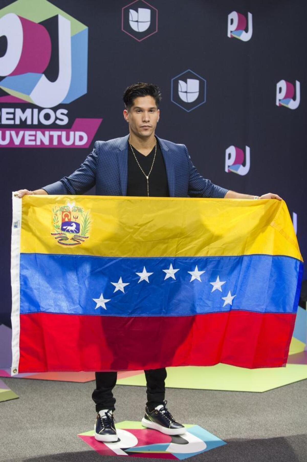 El cantante venezolano Chyno Miranda despliega una bandera de su país a su llegada a la alfombra de la decimocuarta edición de los Premios Juventud el jueves 6 de julio 2017, en Miami, Florida.