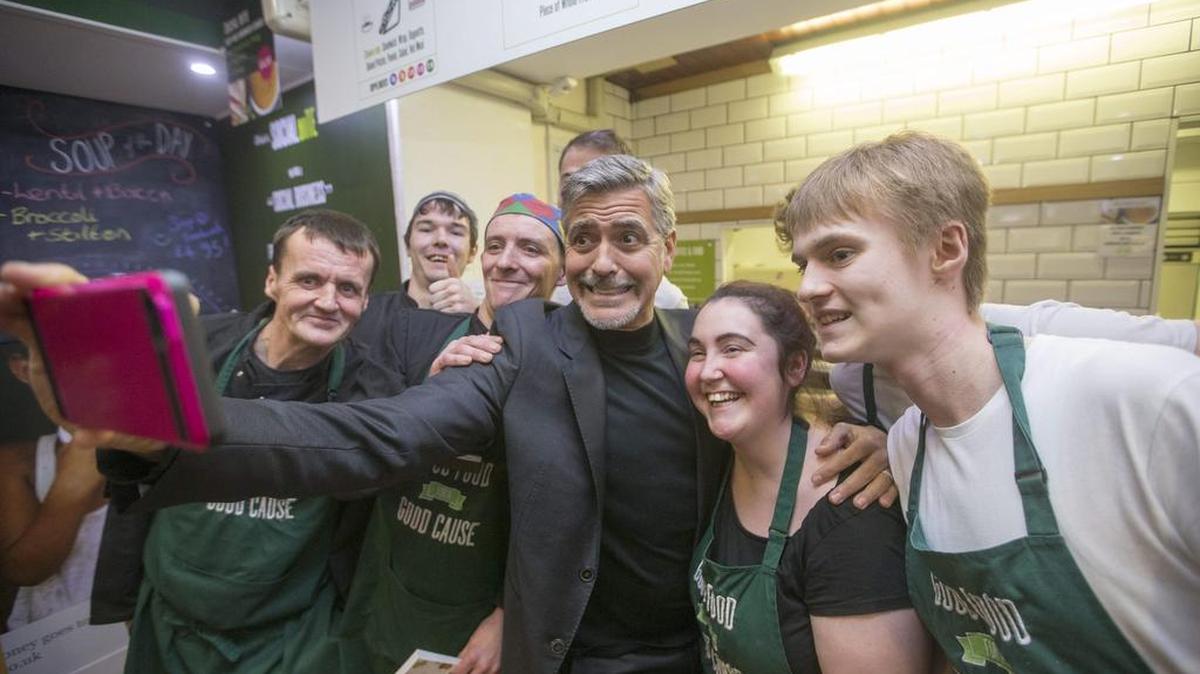 Fotografía facilitada por JSHPIX.CO que muestra al actor estadounidense George Clooney (c) mientras posa con trabajadores de la cafetería Social Bite Cafe, en Edimburgo, Escocia (Reino Unido) hoy, 12 de noviembre de 2015.
