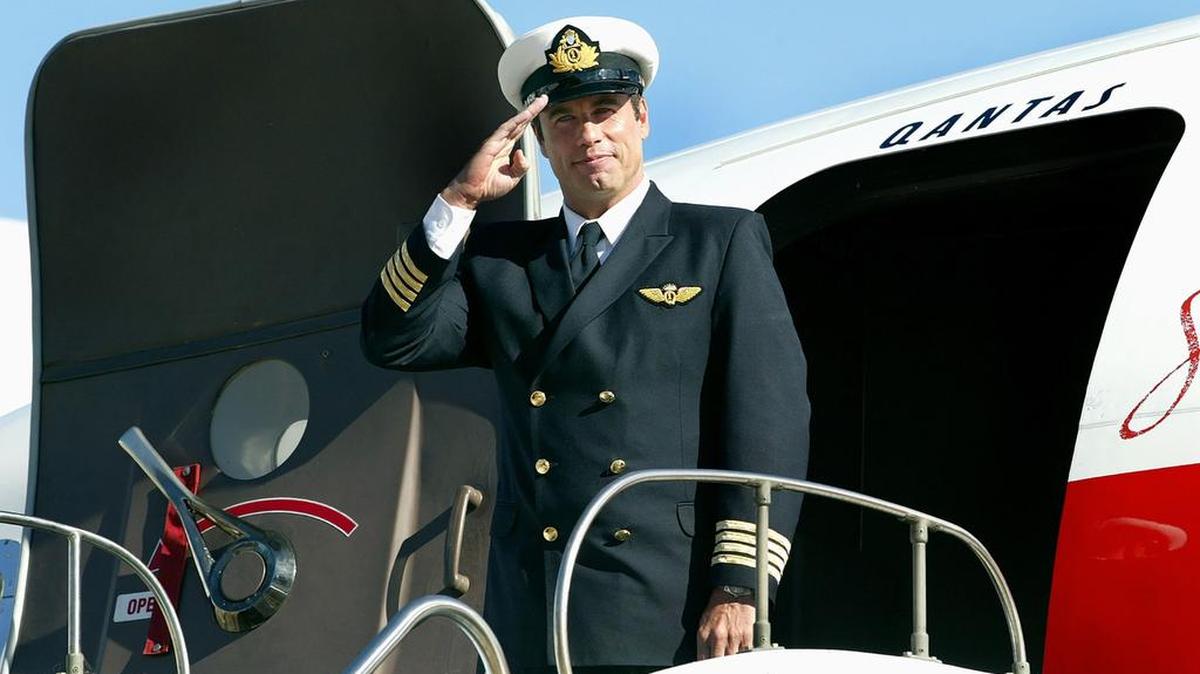 Una foto de archivo tomada el 12 de julio de 2002, muestra a la estrella de Hollywood John Travolta, de pie delante de su Boeing 707 en el aeropuerto de Sydney.