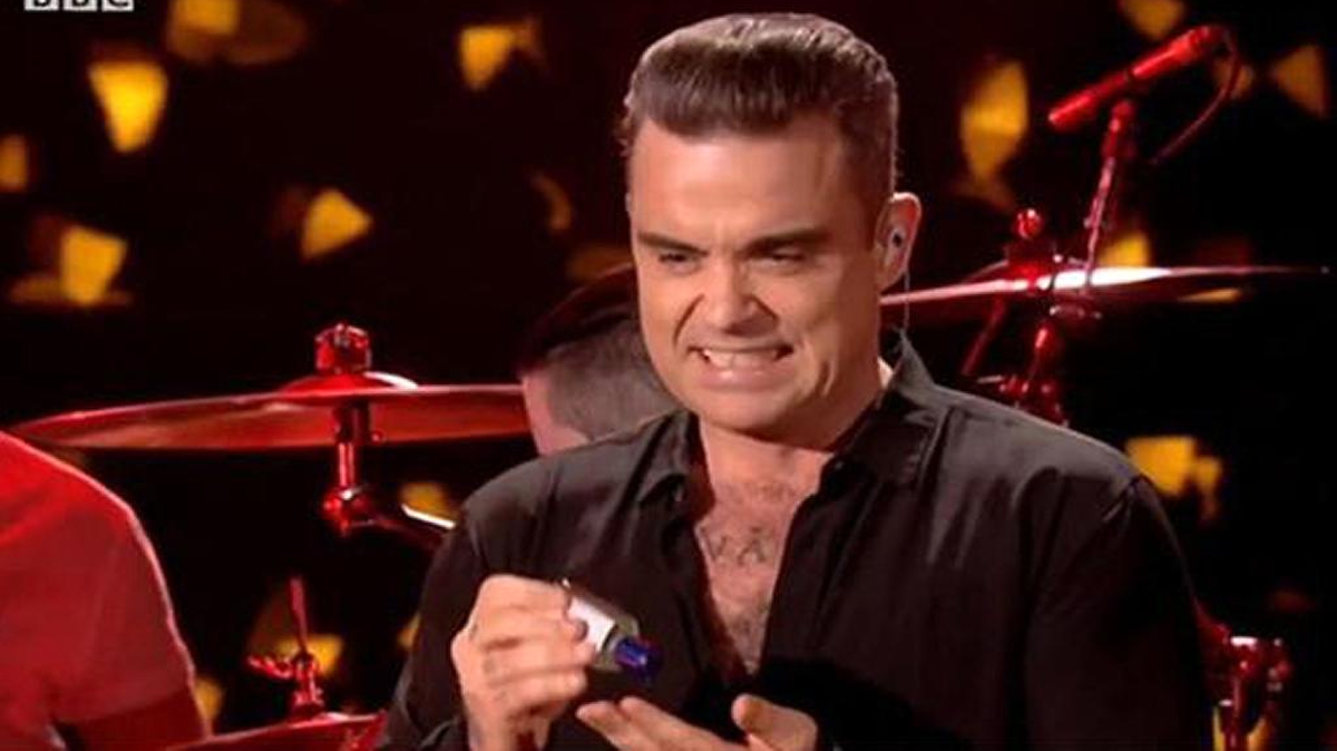 El cantante británico Robbie Williams se desinfectó las manos tras saludar a varios de sus seguidores, durante una presentación en vivo en Londres para las celebraciones de Año Nuevo.