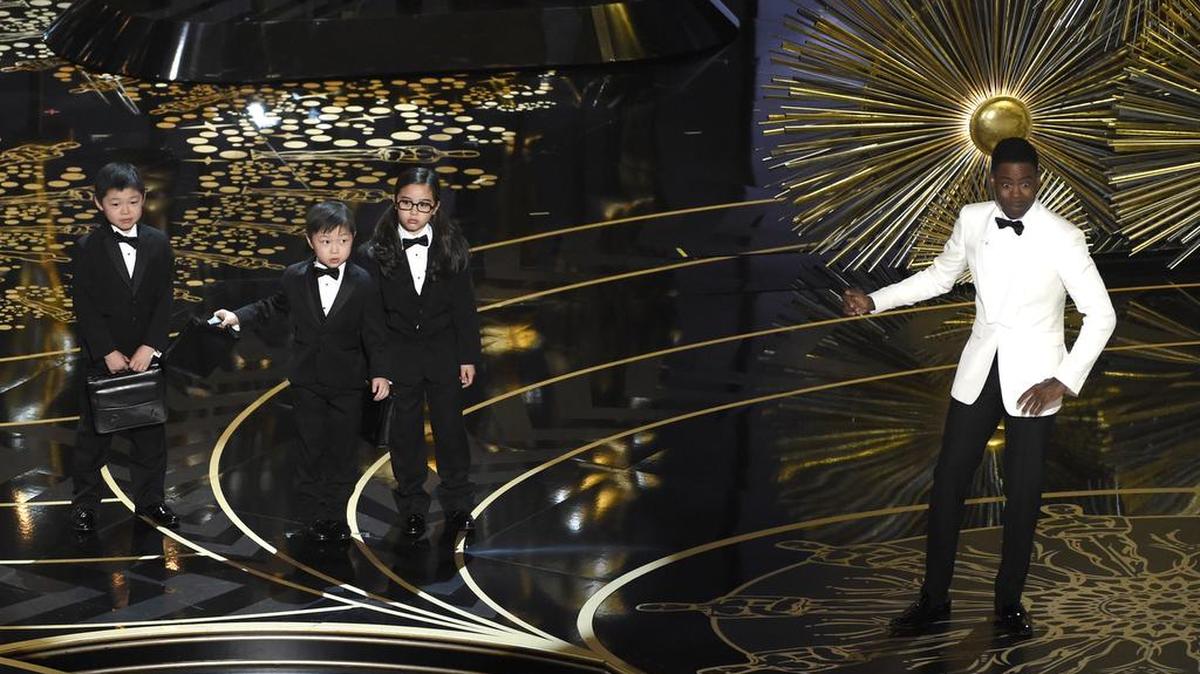 Chris Rock, con tres niños en el escenario de la gala de los premios Oscars en Los Angeles.