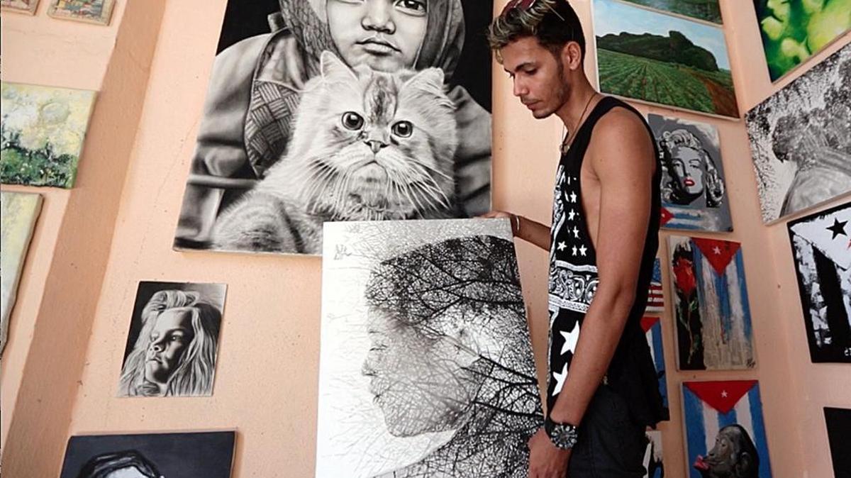 Yanzel Medina Pérez muestra sus cuadros hiperrealistas que se exhiben en Yusi's Art Alliance, una galería manejada por artistas cuentapropistas en Cienfuegos.