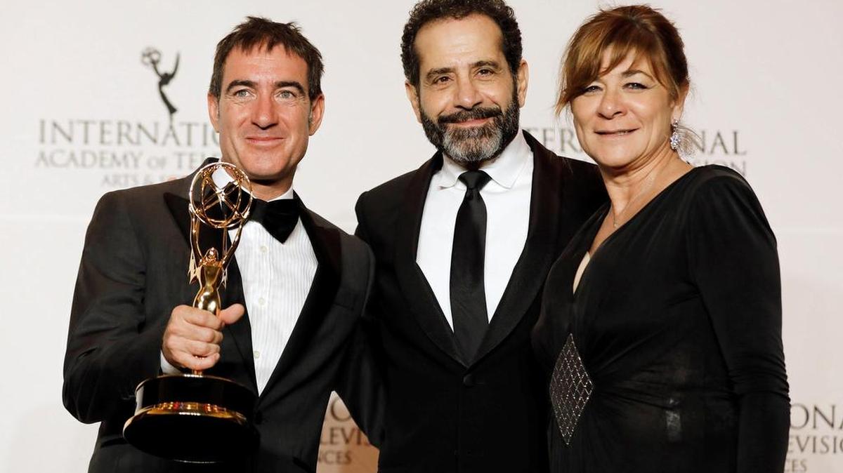El actor estadounidense Tony Shalhoub (c) posa junto al guionista español Alex Pina (i) y la productora ejecutiva Sonia Martínez (d) mientras sostienen su premio a Mejor Serie Dramática por “La casa de papel” durante la ceremonia de entrega de los Premios Emmy Internacional en el hotel New York Hilton, en Nueva York.