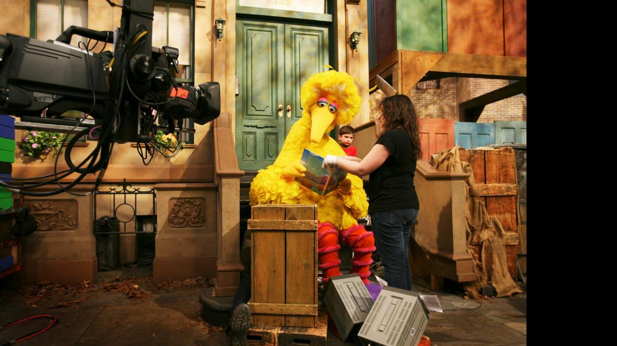 
Michelle Hickey, de los Muppet, coloca un libro para Big Bird, cuya voz es la del actor Carroll Spinney, para que lea al niño Connor Scott en las filmación del programa Sesame Street, en el 2008. 
