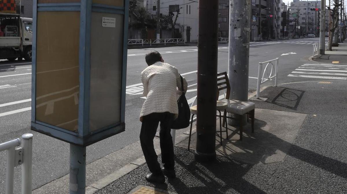 Una mujer mayor espera un autobús en una parada de autobús en Tokio, el lunes 20 de febrero de 2017.