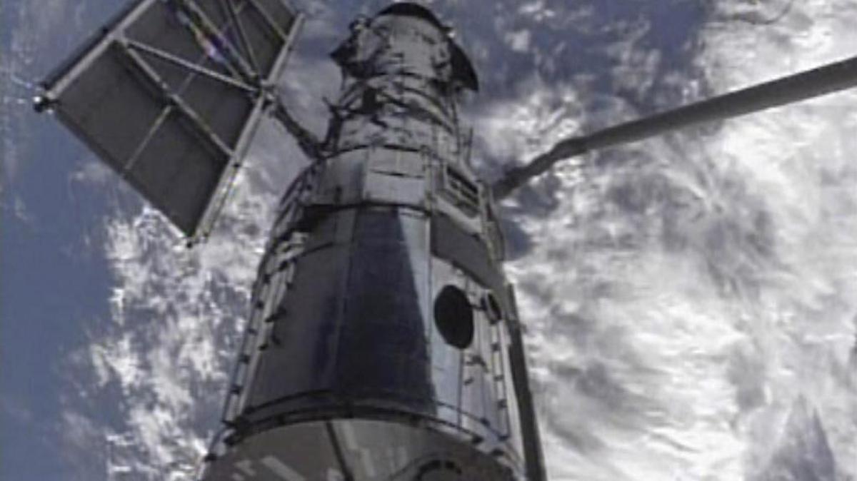 En imagen de la NASA, se muestra el telescopio espacial Hubble sostenido por el brazo robótico del Shuttle Atlantis, el 13 de mayo del 2009.